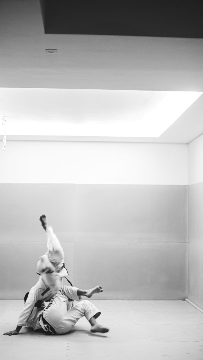 Two martial artists in a dynamic jiujitsu move captured in monochrome.