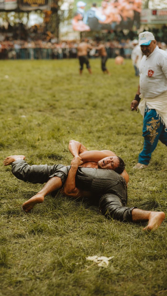 Intense wrestling match capturing athletes in action on a grassy field.